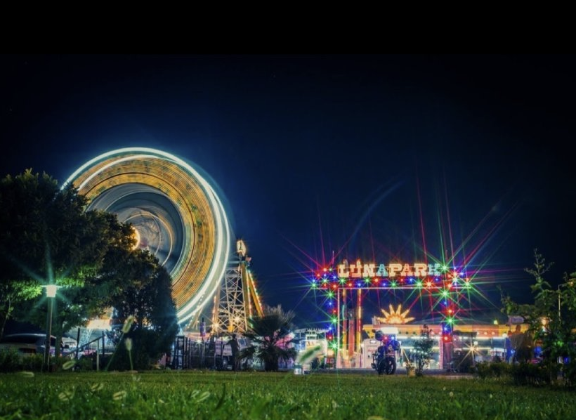 Kurt Lunapark'ta gece dönen ışıl ışıl dönme dolap ve neon LUNAPARK tabelası